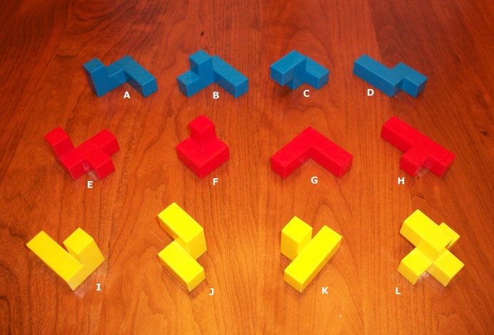 Photo of the 12 pieces of the Tetris Cube labeled A through L.