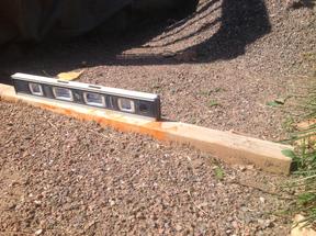 Close-up of buried 2x4 used as leveling guide for crusher fine base for flagstone patio.